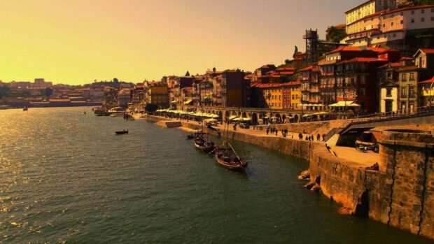 Riverside cityscape of Portugal with traditional boats and historic buildings during sunset