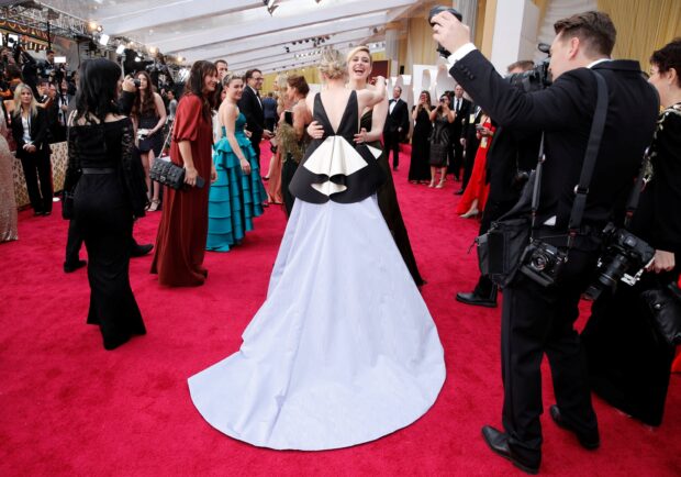 Woman in elegant dress celebrates at red carpet event with crowd around