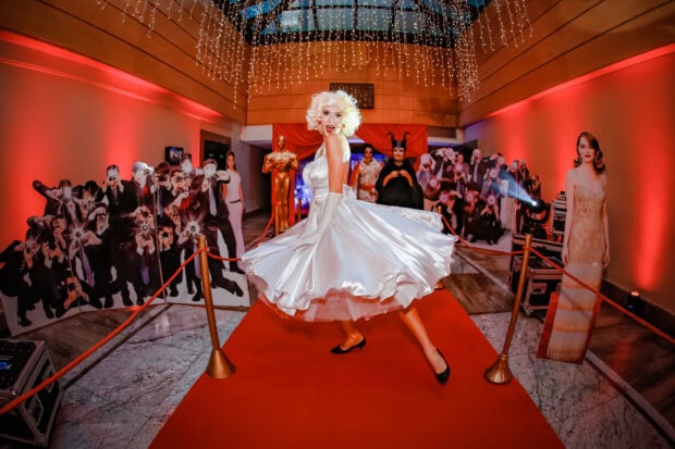 Woman in elegant white dress on red carpet surrounded by red carpet ceremony decorations