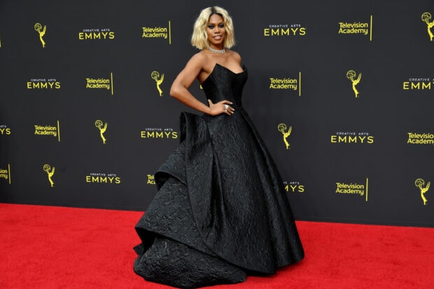 Woman wearing an elegant black dress at a red carpet event with Emmy awards decor