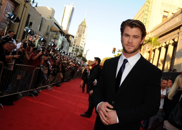 A man in a black suit standing on the red carpet at a celebrity event