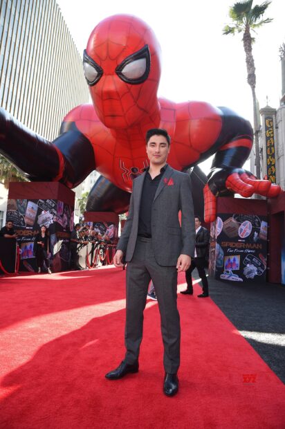 Man on red carpet with giant Spider Man balloon at event
