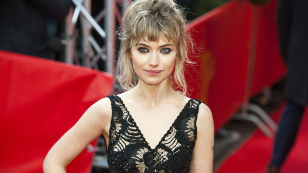 Woman with wavy blonde hair wearing a black lace dress on the red carpet