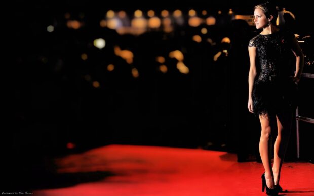 Woman standing on red carpet at a glamourous event wearing a black dress