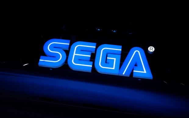 Blue Sega logo sign illuminated at night with a dark background