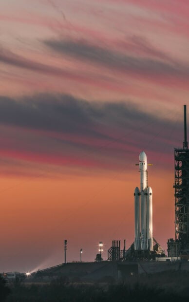 SpaceX rocket standing on launch pad during sunset with colorful sky