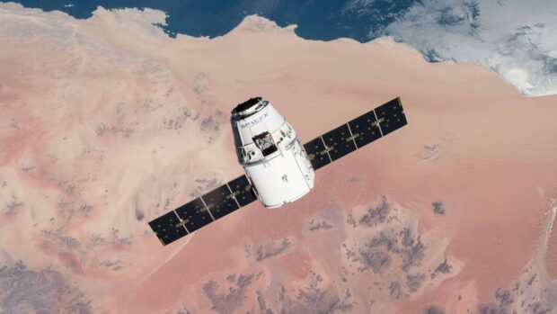 SpaceX spacecraft orbiting over desert terrain in space