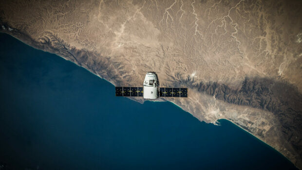 A Spacex spacecraft orbiting above the Earth's coastline in space