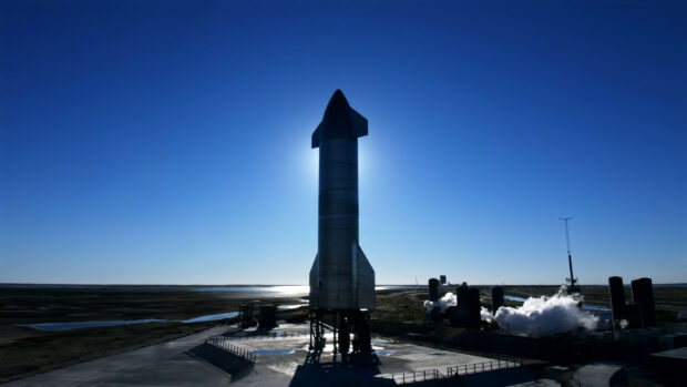 SpaceX Starship rocket standing on launch pad at sunset with clear blue sky