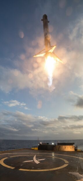SpaceX rocket booster landing on drone ship in the ocean during sunset