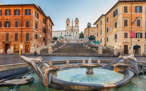 Historic Spanish Steps Rome with sea shell fountain and old buildings in city center