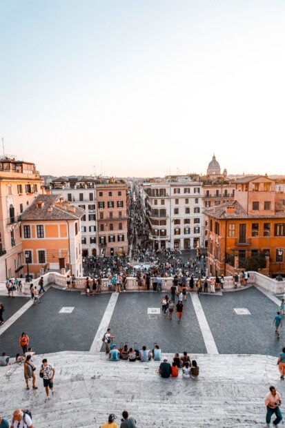 Crowded Spanish Steps Rome at sunset with historic buildings and tourists on stairs