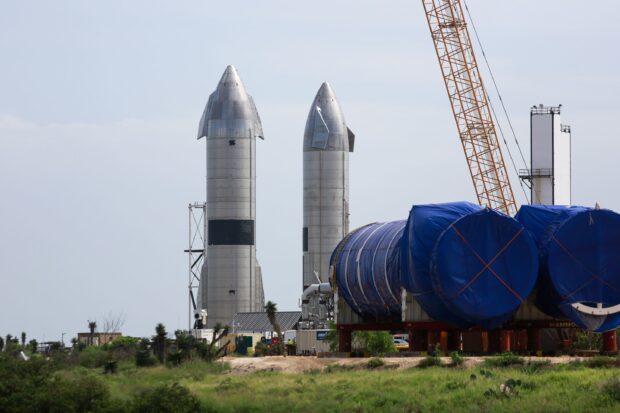Two large starship prototypes standing on the launch site with industrial equipment nearby