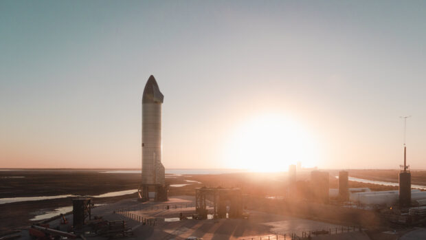 Starship standing tall at sunset on launchpad in desert landscape