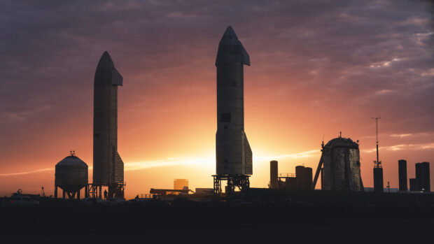 Starship rockets standing on the launch site during a vibrant sunset sky