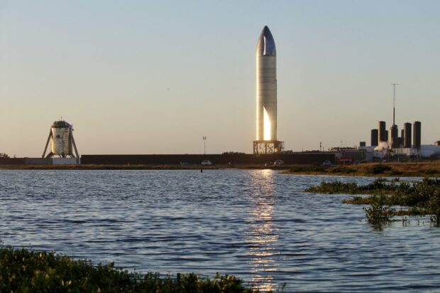 Starship soaring above the water reflecting the sunlight during sunset