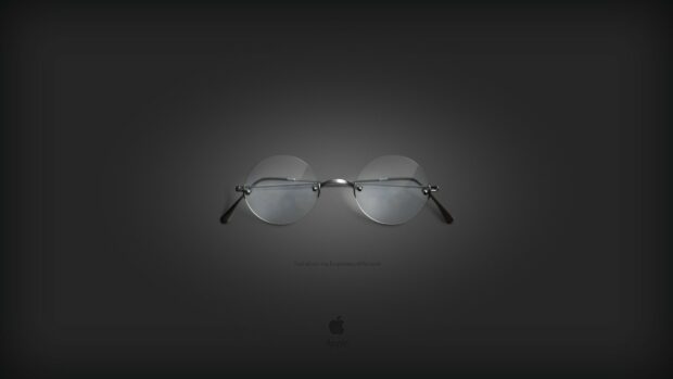 Round glasses symbolizing Steve Jobs are placed on a dark background with Apple logo below