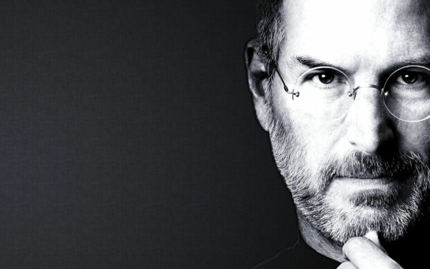 Steve Jobs portrait with glasses and beard in a thoughtful pose on black background