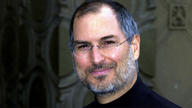 Steve Jobs with glasses and beard smiling in a close up portrait