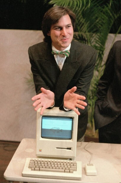 Young Steve Jobs presenting an early computer model with enthusiasm in a vintage setting