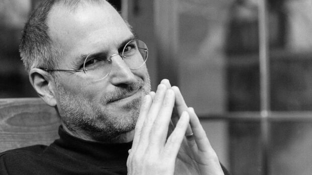 Steve Jobs portrait in black and white with thoughtful expression and glasses