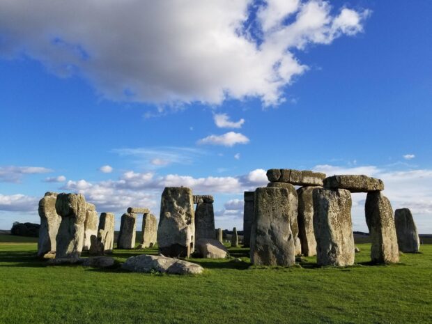 Ancient Stonehenge structure under a blue sky with scattered clouds