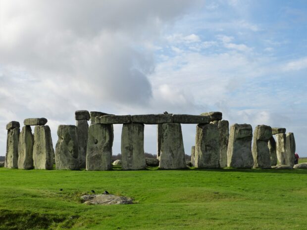 Ancient stone structures at Stonehenge on a green grassy field under a cloudy sky