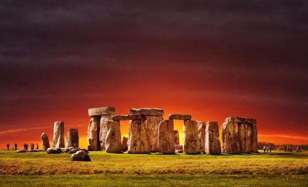 Ancient Stonehenge monument standing tall under a dramatic sunset sky