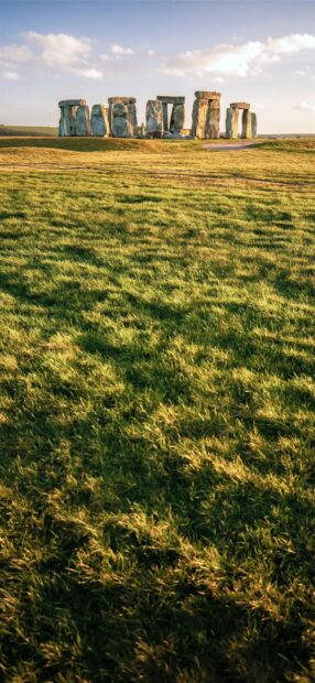 A scenic view of Stonehenge with lush green grass under a blue sky in Stonehenge