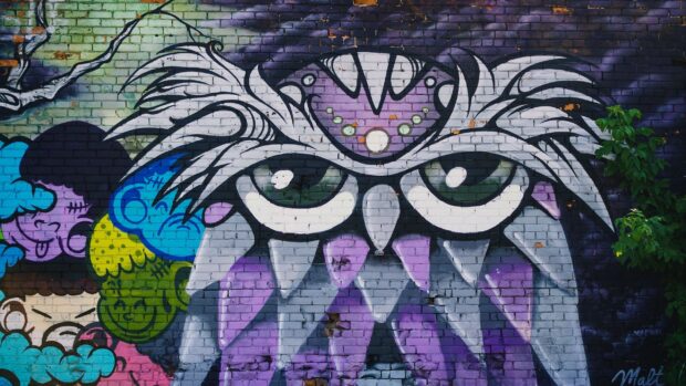 Graffiti art with owl eyes and colorful abstract shapes on a brick wall