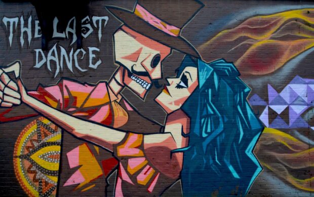 A street art mural showing a dancing skeleton and a woman with blue hair in vibrant colors