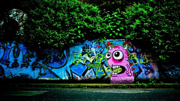 A colorful street art character with big eyes and mushrooms on a wall surrounded by green foliage