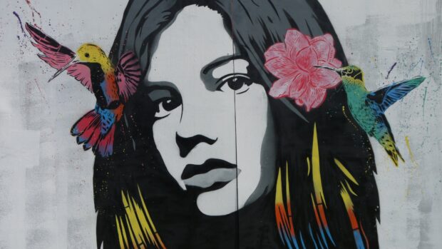 A street art portrait of a woman with colorful hummingbirds and a pink flower in her hair