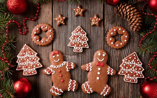 Gingerbread sweets decorated as Christmas trees and figures on wooden surface