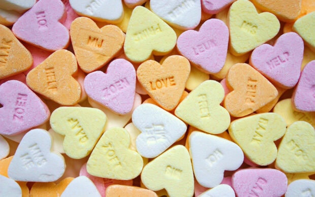 Heart shaped sweets with various messages in pastel colors on a flat surface