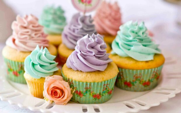 Colorful cupcakes with creamy frosting and a rose on a decorative plate