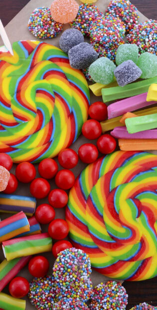 Colorful rainbow swirl candies and assorted gummy sweets arranged closely together