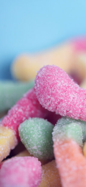 Close up of colorful sweets covered with sugar crystals on a blue background