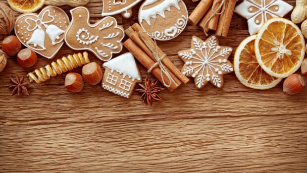 Gingerbread cookies and dried orange slices with cinnamon sticks on wooden surface