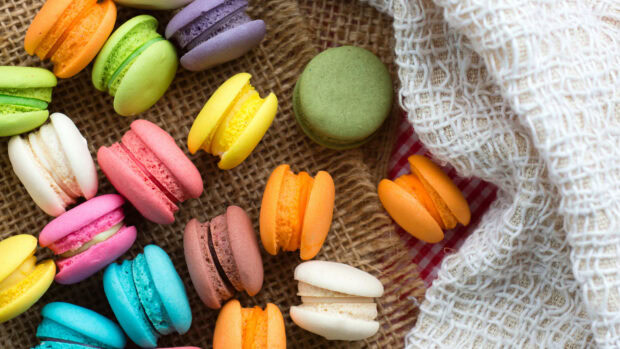 Colorful macarons arranged on a textured surface with fabric in the background