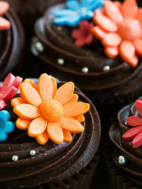 Close up of colorful flower decorations on rich chocolate cupcakes sweets