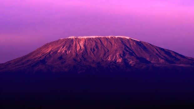 Snow capped Kilimanjaro mountain in Tanzania at sunset with purple sky