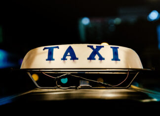 Close up of taxi sign glowing at night showing taxi letters clearly