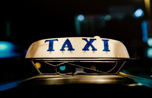Close up of taxi sign glowing at night showing taxi letters clearly