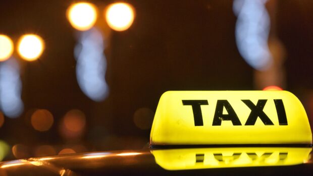 Yellow taxi sign glowing at night with city lights in the background