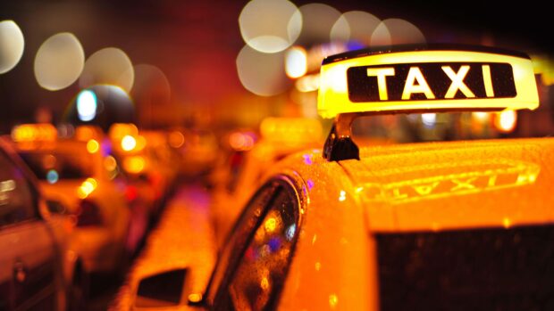 Yellow taxi sign glowing brightly on a rainy night in the city