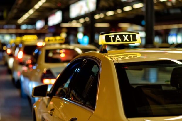 Yellow taxi waiting in line at night in an urban area with blurred lights in the background