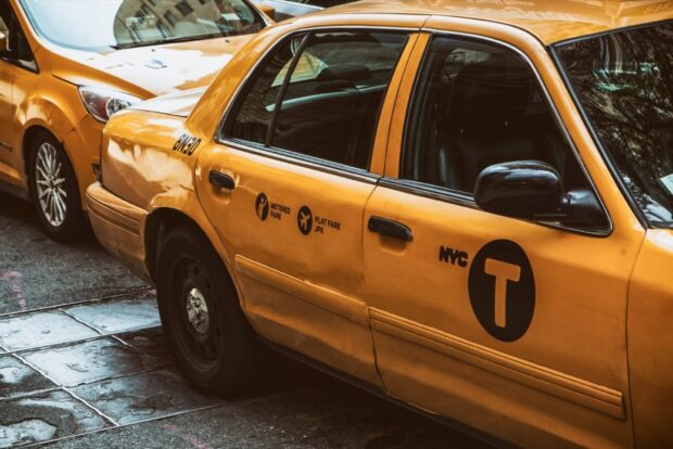 Yellow taxi with NYC logos parked on the street in a city environment