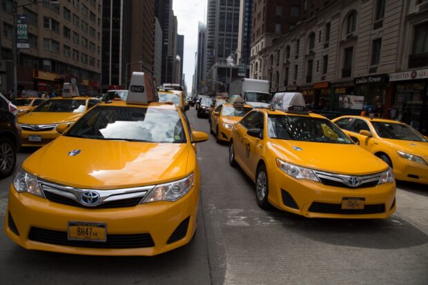 Yellow taxis lined up on a busy city street with tall buildings in the background