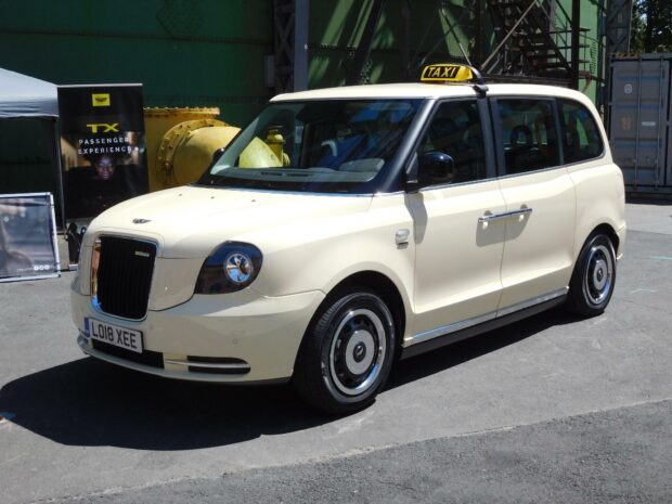 Cream colored taxi parked on the street with a taxi sign on the roof